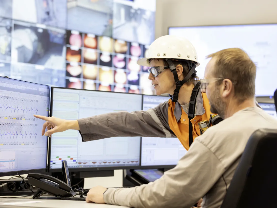 Collega's wijzen naar een scherm in de controlezaal van de hoogovens